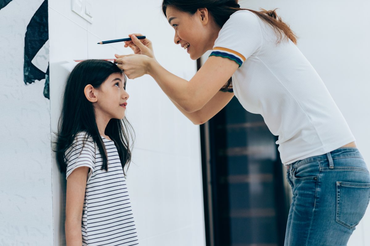 mother-measuring-her-daughters-height