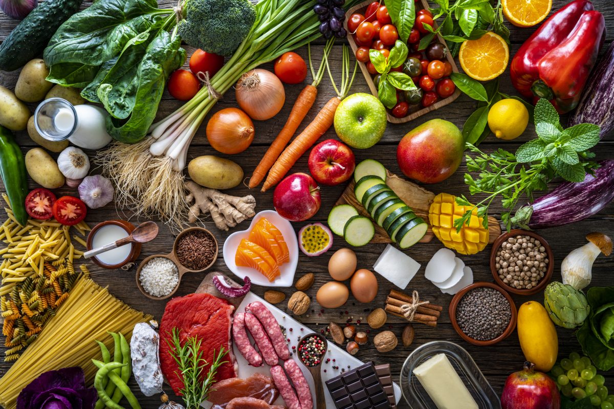 varied-food-carbohydrates-protein-vegetables-fruits-dairy-legumes-on-wood