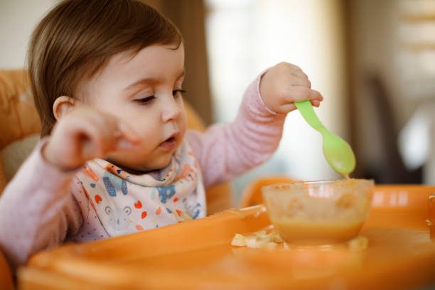 little-baby-girl-eating-food-on-high-chair