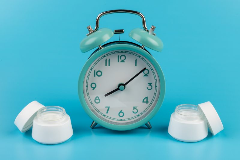 morning-concept-or-time-to-skin-care-alarm-clock-showing-8-oclock-and-cream-face