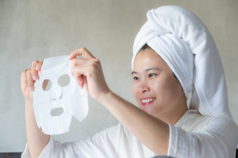 smiling-asian-woman-holding-a-facial-mask-before-applying-to-her-face