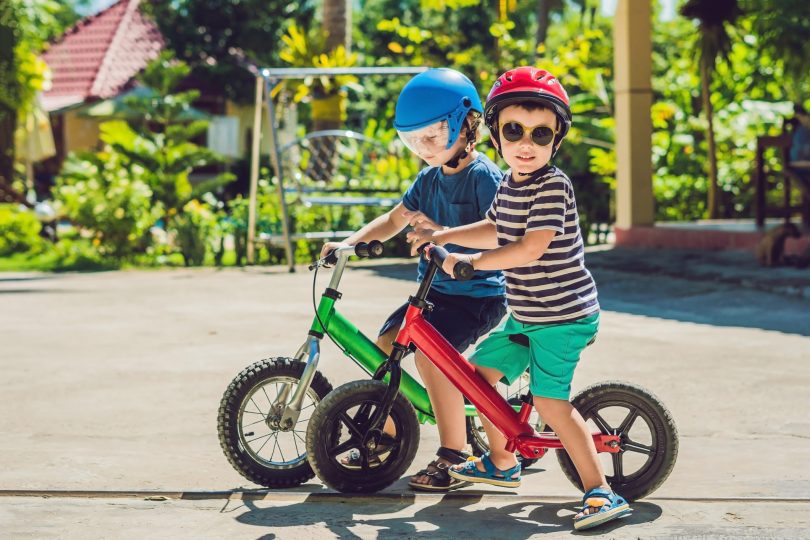 two-little-boys-children-having-fun-on-balance-bike-on-a-country-tropical-road