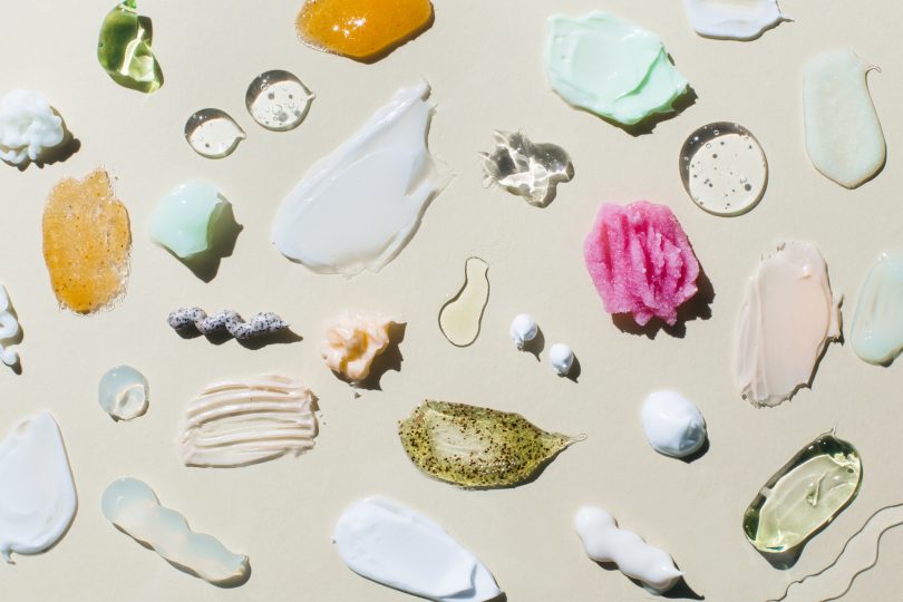 set-textured-multicolored-smears-cosmetic-products-on-beige-background-samples-of-creams-face-gel-scrubs-with-exfoliating-particles-serum-flat-lay-top-view
