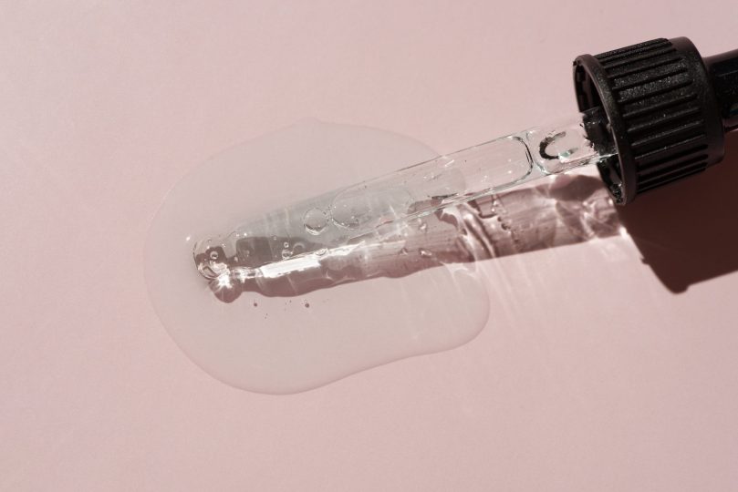 liquid-oil-serum-drop-in-pipette-isolated-on-pastel-pink-background-retinol-aha-bha-acid-collagen-skincare-fluid-photo-with-shallow-depth-of-field-gold-essence-in-dropper-for-beauty-treatment