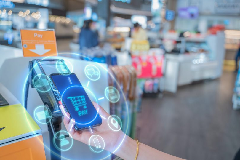 internet-of-things-and-mobile-payment-conceptclose-up-hand-holding-smart-phone-with-communication-icons-paying-through-terminal-connection-and-wireless-network-technology