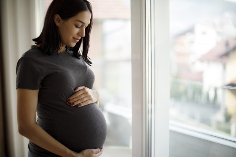 portrait-of-young-happy-pregnant-woman-standing-by-the-window