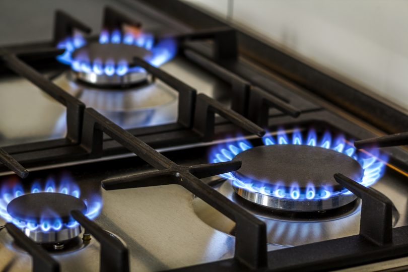 natural-gas-burning-on-kitchen-gas-stove-in-the-dark-panel-from-steel-with-a-gas-ring-burner-on-a-black-background-close-up-shooting