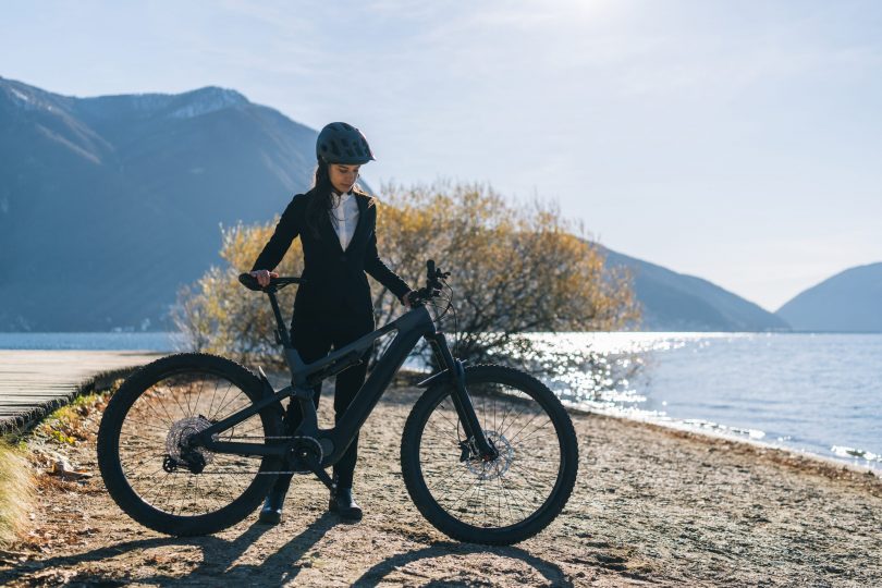 business-woman-with-e-bike-relaxes-by-lake