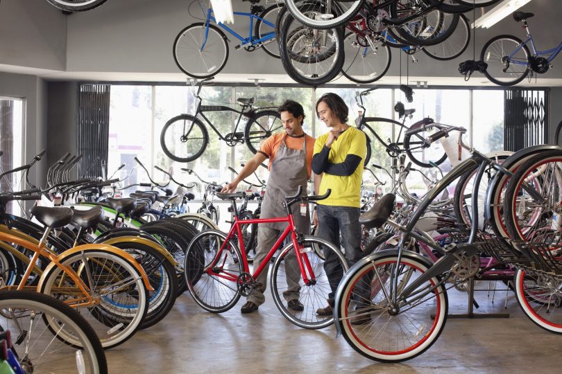 bike-shop-owner-helping-customer-choose-bicycle