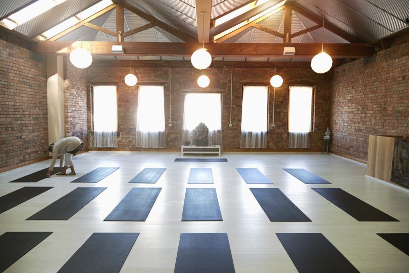 caucasian-woman-arranging-mats-in-yoga-studio