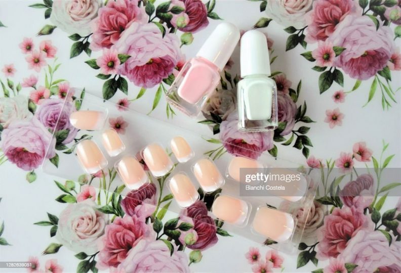 false-nails-and-polishes-on-a-flower-background-top-view