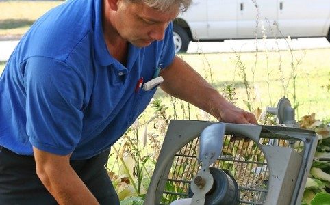 man-in-blue-shirt-with-gray-hair-repairing-an-ac-outdoors