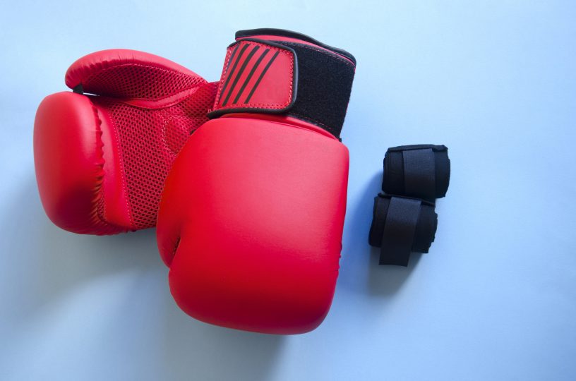 red-boxing-gloves-and-black-bandages-against-blue-background-boxing-equipment