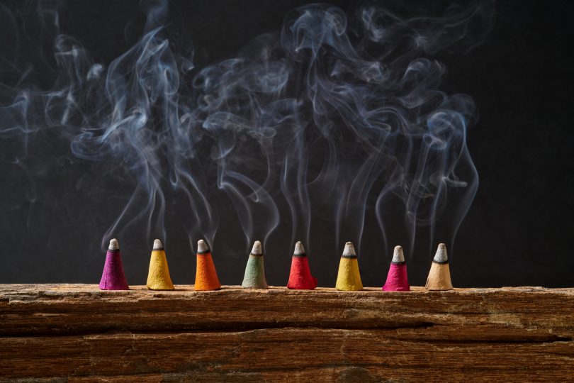 incense-sticks-on-old-wood-with-smoke-and-black-background